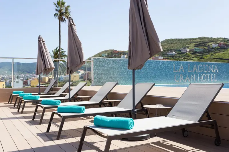 Transats bleus turquoise disposés autour d'une piscine en terrasse.