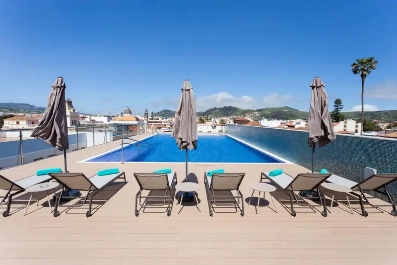 Terrasse avec piscine et chaises longues ensoleillées.