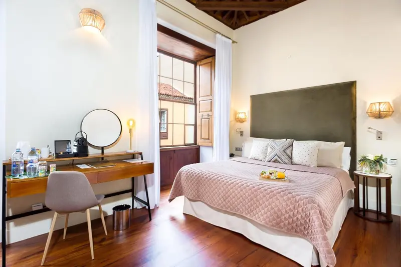 Une chambre lumineuse avec un grand lit et un coin bureau.