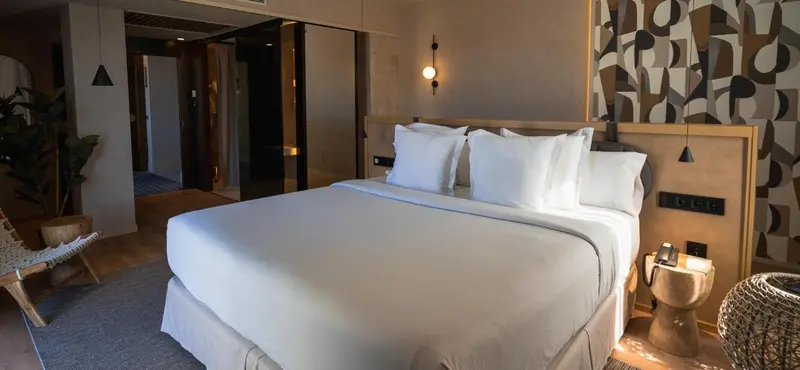 Une chambre lumineuse avec un grand lit recouvert d'une couette blanche et des oreillers.
