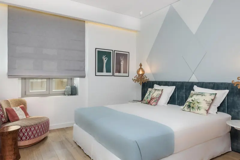 Une chambre lumineuse avec un lit recouvert d'une couverture bleue et de coussins.