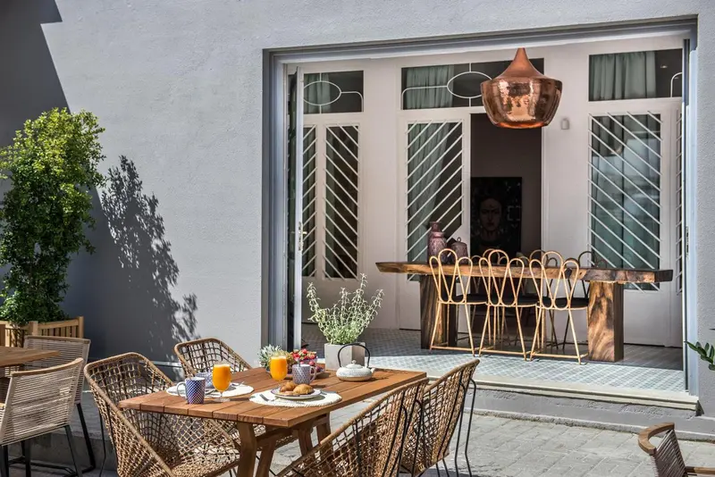 Une table et des chaises en osier sont disposées sur une terrasse carrelée.