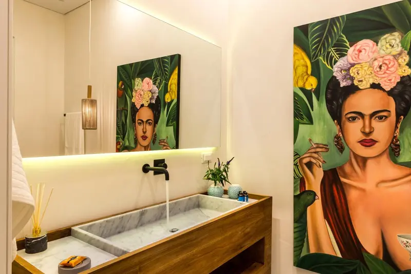 Une salle de bain lumineuse avec un lavabo en marbre et une grande peinture murale.
