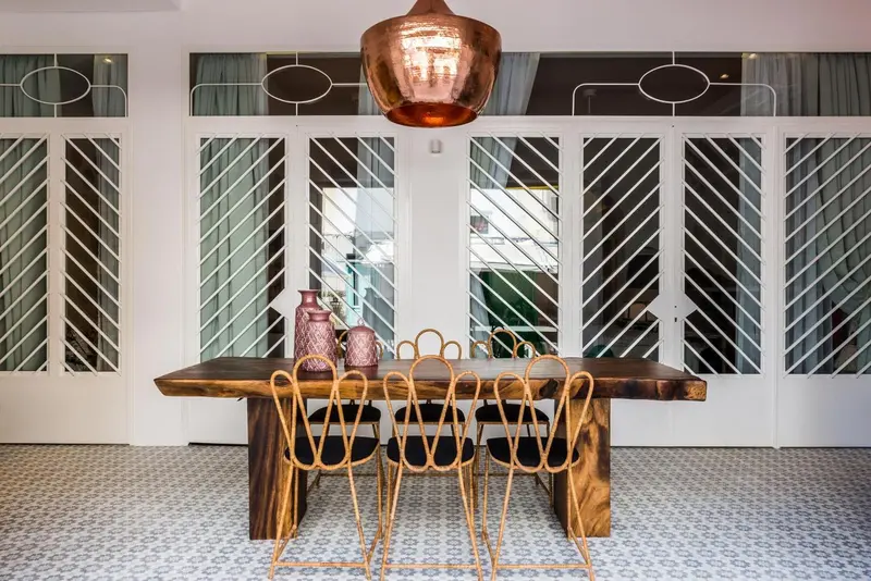Une table en bois massif est entourée de chaises dans une salle à manger lumineuse.
