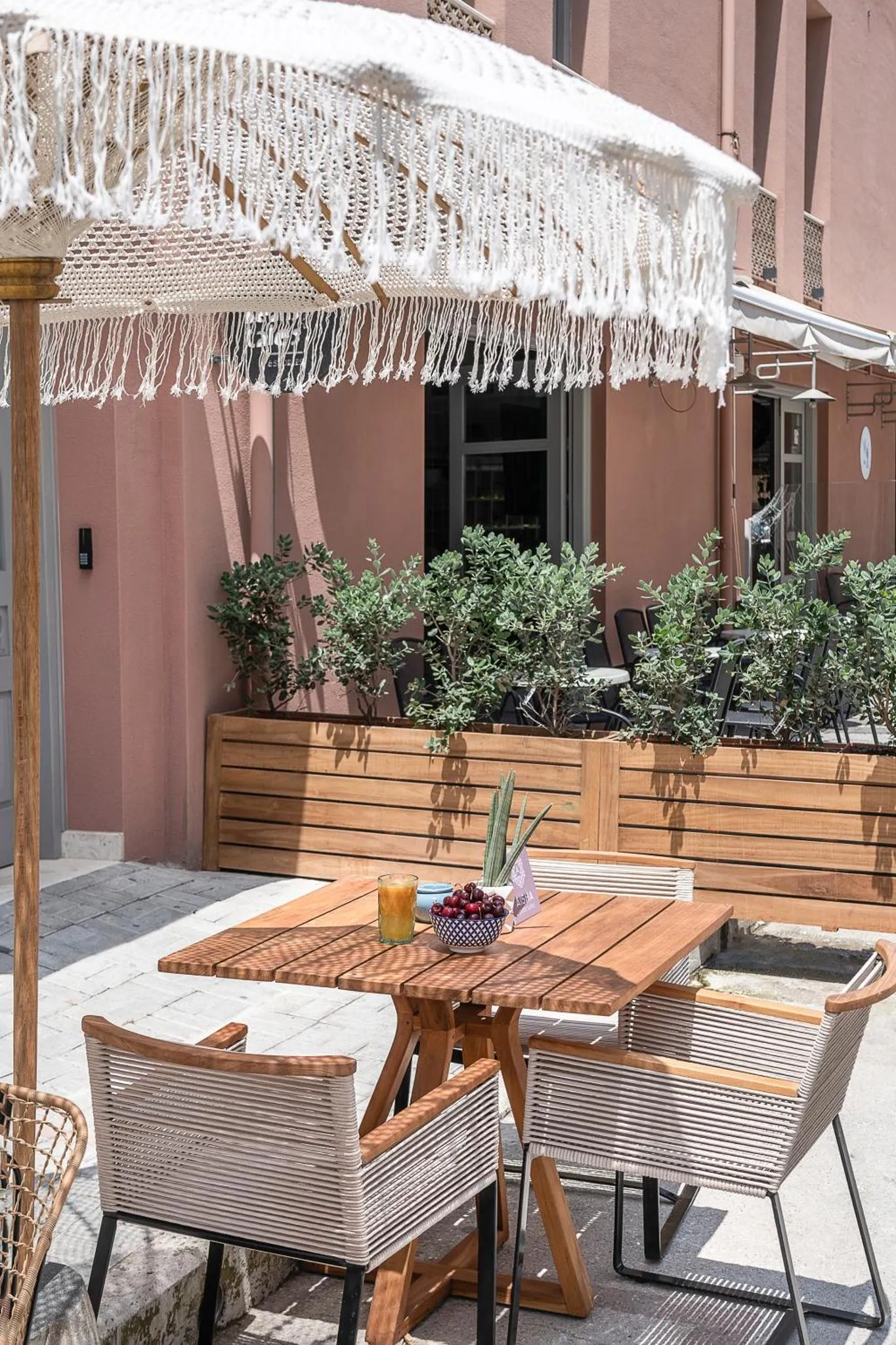 Une table en bois avec des boissons et des fruits sur une terrasse ombragée.