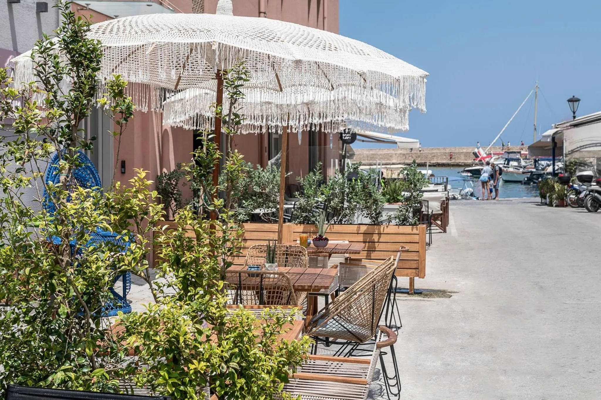 Terrasse ombragée avec tables et chaises en bord de mer.