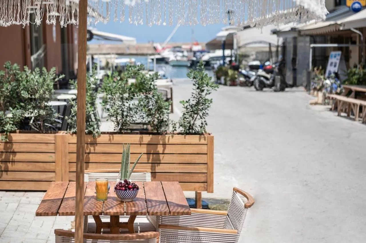 Une table en bois avec des boissons et des fruits est mise en scène sur une terrasse ensoleillée.