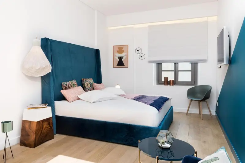 Une chambre moderne avec un grand lit recouvert d'une courtepointe blanche et de coussins colorés.
