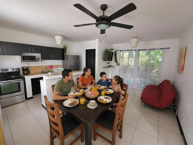 Une famille prend son petit-déjeuner autour d'une table dans une pièce lumineuse.
