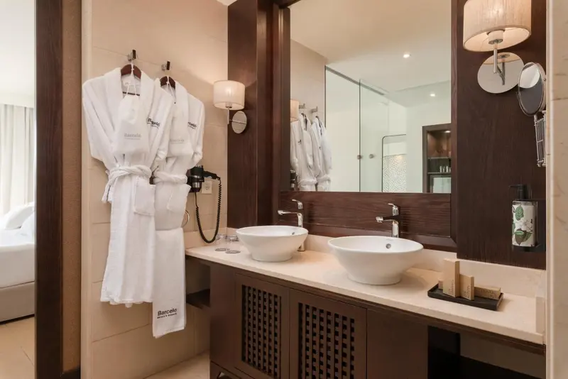 Une salle de bain moderne avec deux vasques et des peignoirs blancs.