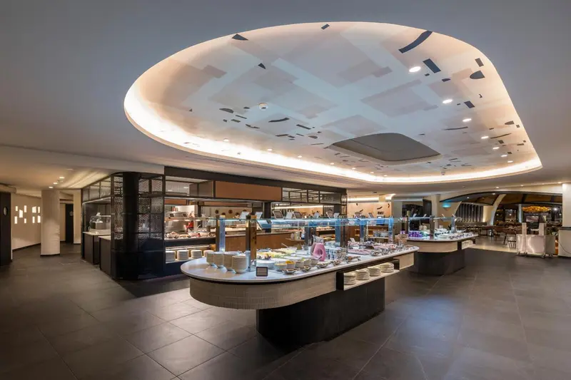 Un buffet de plats variés est présenté dans une salle lumineuse et moderne.