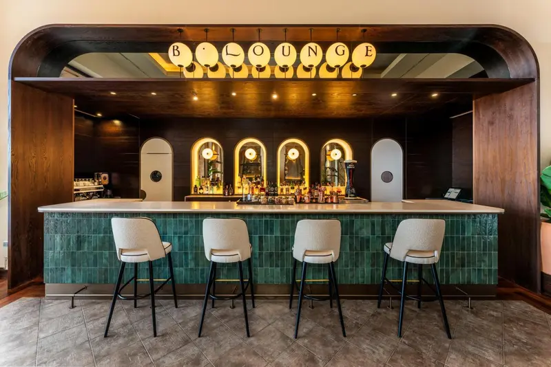 Un comptoir de bar turquoise avec des tabourets et des bouteilles.