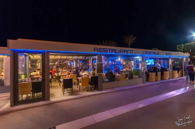 Façade d'un restaurant illuminé avec des clients attablés.