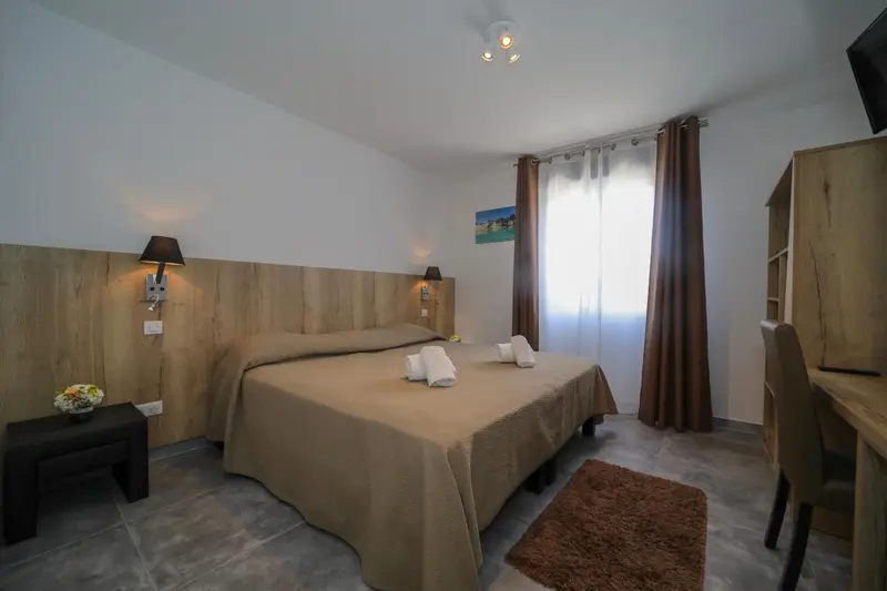 Une chambre lumineuse avec un grand lit et un bureau.