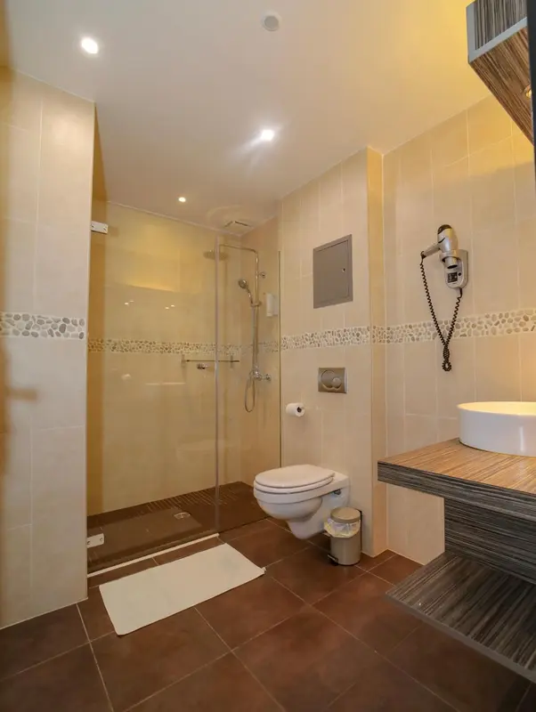 Une salle de bain claire avec douche à l'italienne et lavabo.