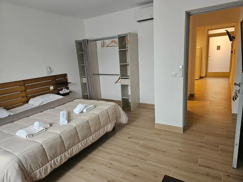 Une chambre lumineuse avec un lit double et un espace ouvert sur une autre pièce.