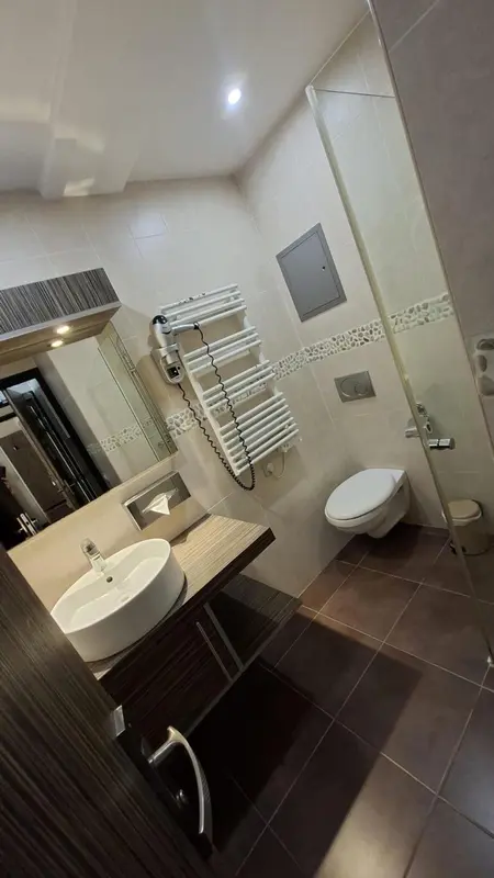 Une salle de bain moderne avec carrelage beige et mobilier en bois sombre.