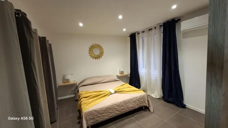 Une chambre à coucher avec un lit recouvert d'une couverture jaune et un décor mural en forme de soleil.