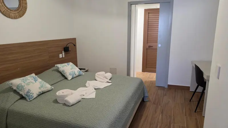 Une chambre lumineuse avec un grand lit recouvert d'une courtepointe et de coussins.