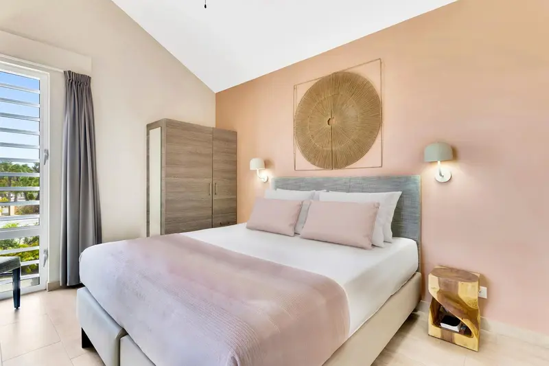 Une chambre lumineuse avec un lit double et une décoration murale.