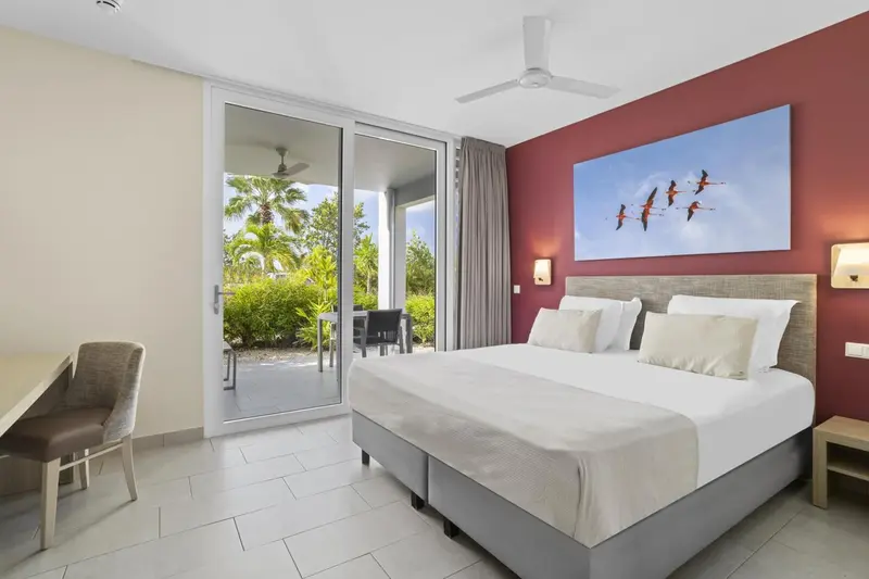 Une chambre lumineuse avec un grand lit et un accès à une terrasse.