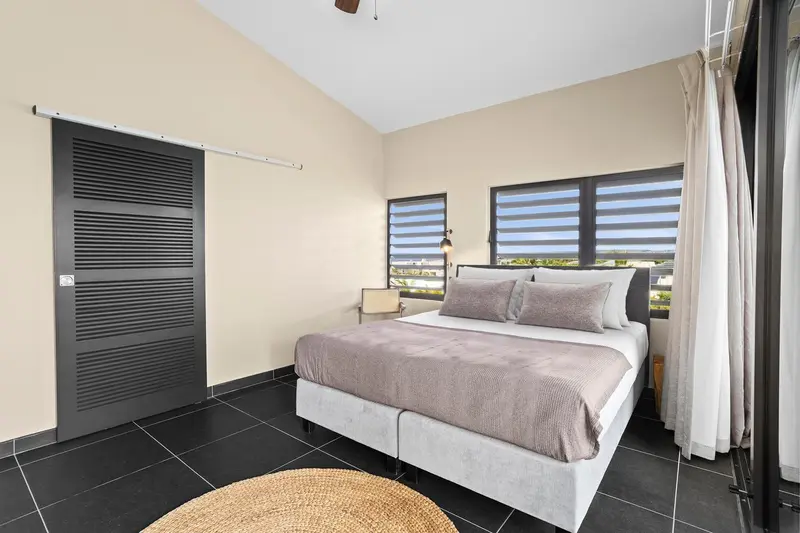 Une chambre lumineuse avec un grand lit et un accès à une vue extérieure.