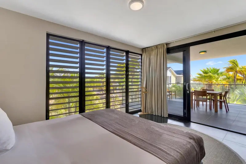 Une chambre lumineuse s'ouvre sur une terrasse avec vue sur la végétation.
