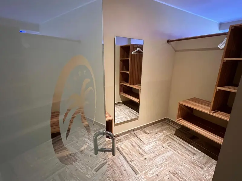 Un dressing avec étagères en bois et porte vitrée décorative.