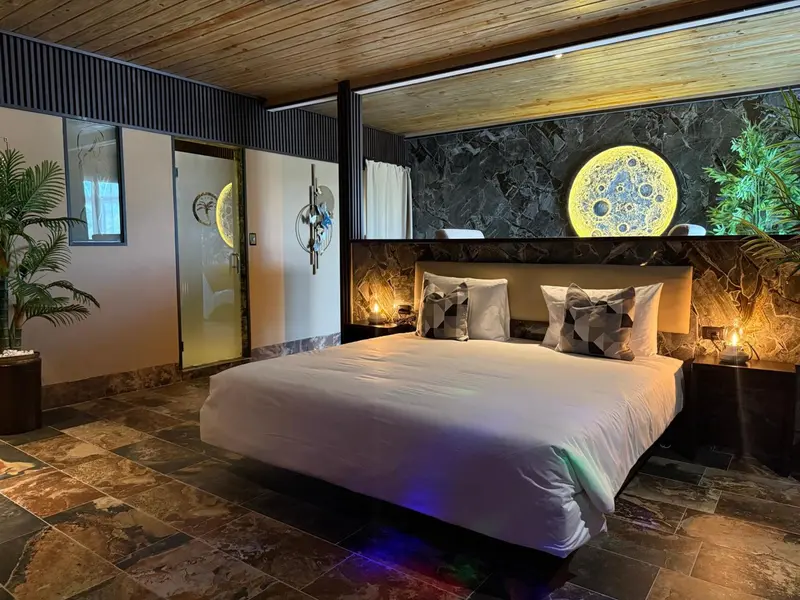 Une chambre lumineuse avec un grand lit recouvert d'une couette blanche et de coussins.