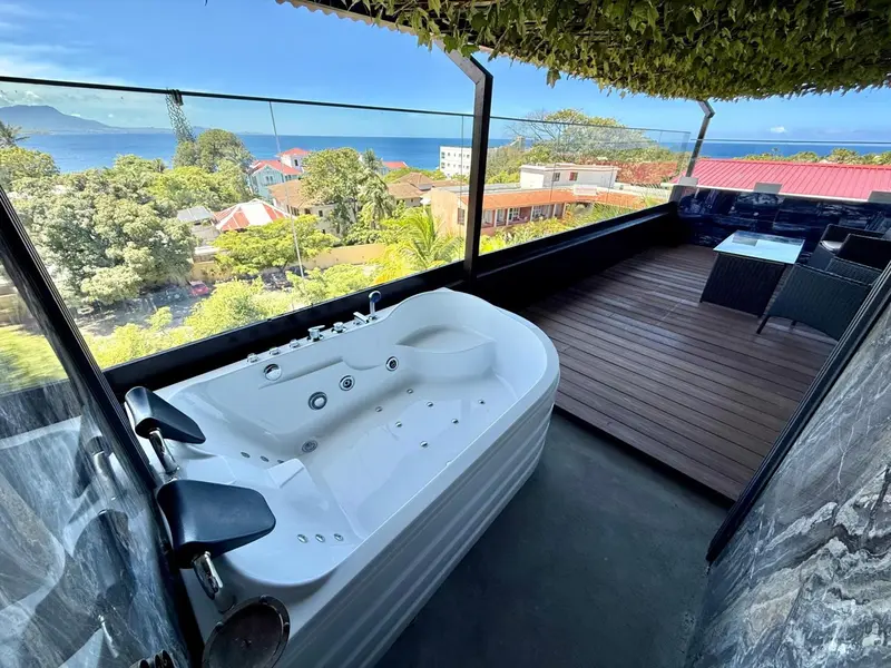 Un jacuzzi extérieur offre une vue dégagée sur la mer et la végétation.