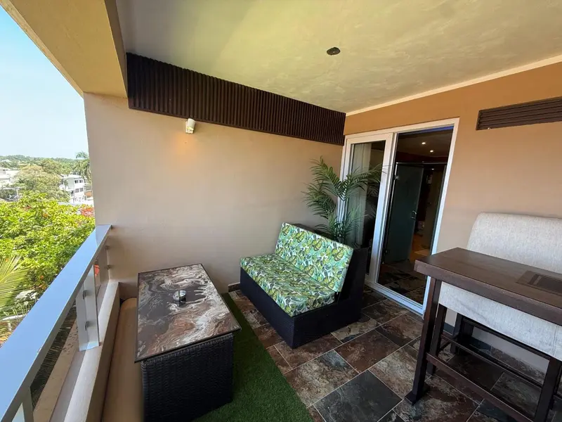 Balcon aménagé avec salon et table basse donnant sur un paysage verdoyant.