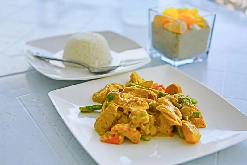 Assiette de riz blanc, de poulet au curry et de légumes.