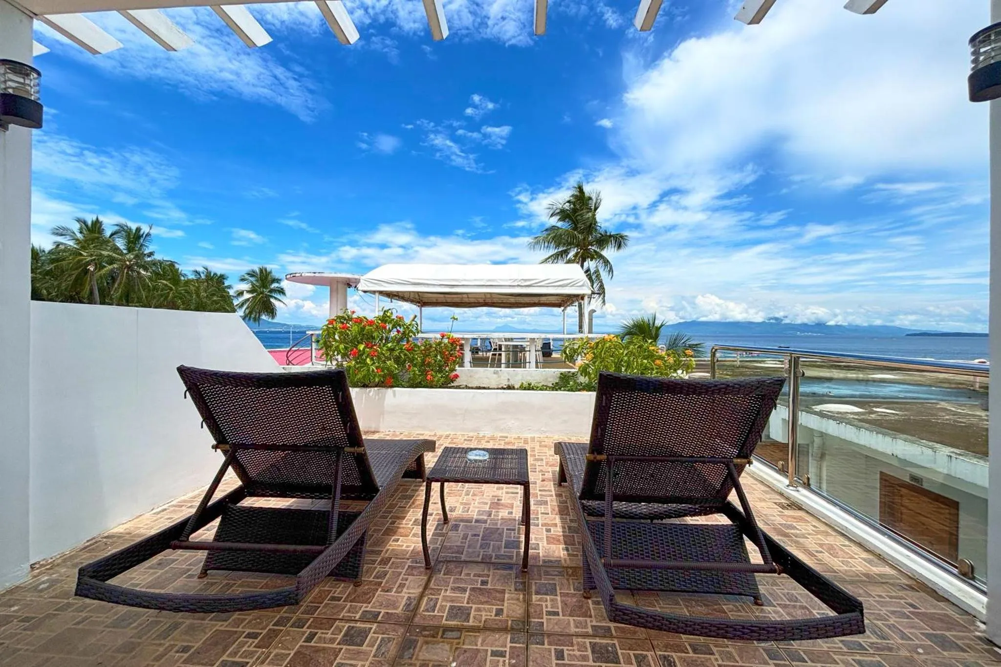 Deux transats invitent à la détente sur une terrasse ensoleillée avec vue sur la mer.