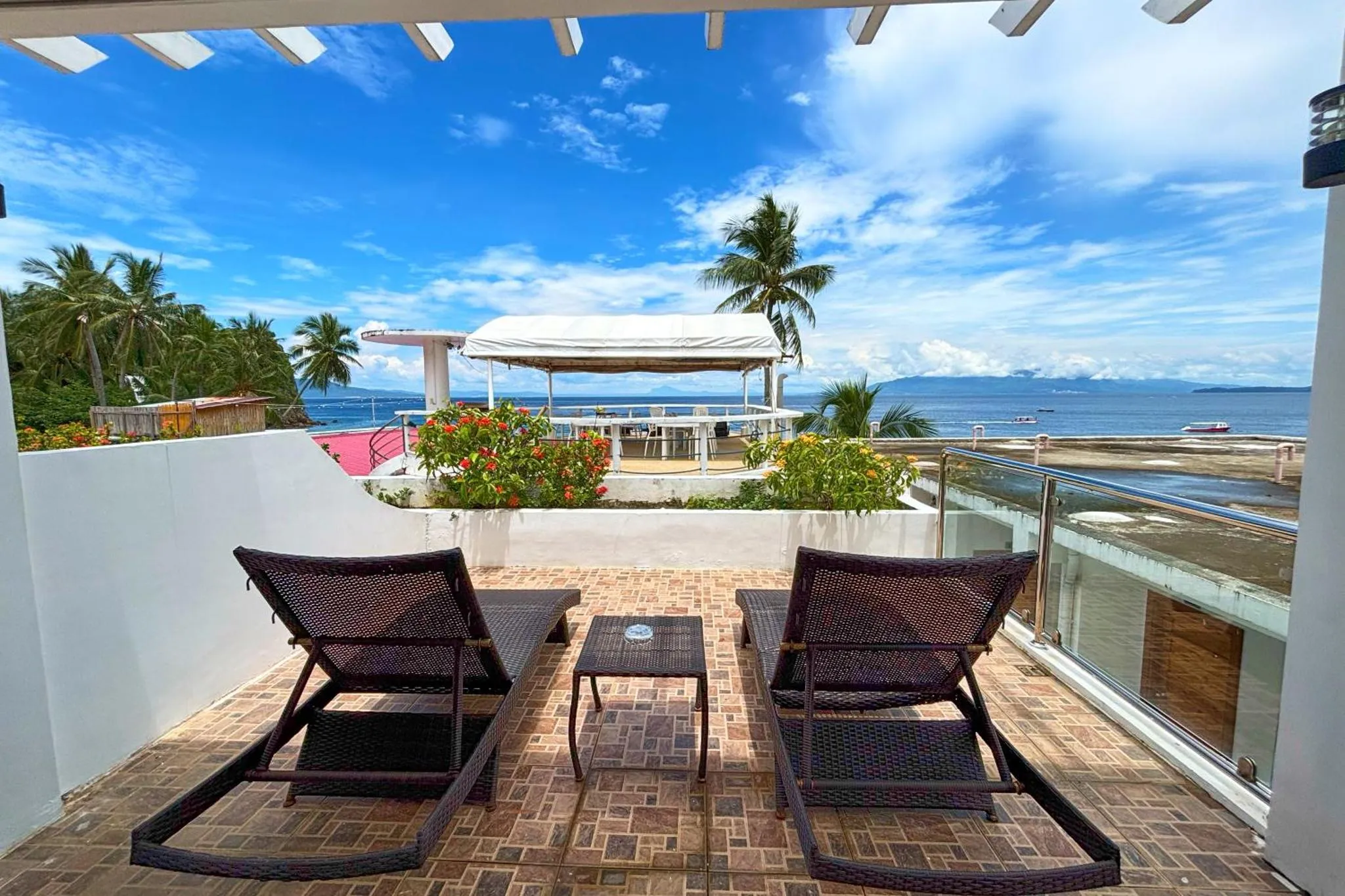 Deux transats invitent à la détente sur une terrasse ensoleillée avec vue sur la mer.