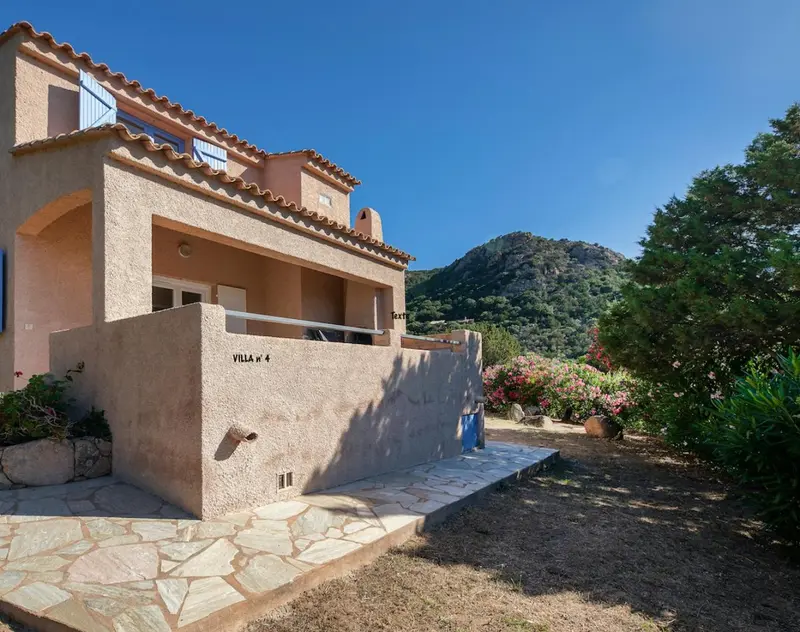 Façade d'une maison basse avec une terrasse et un jardin.