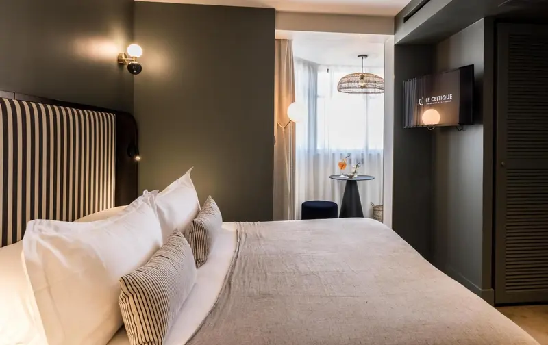 Une chambre avec un grand lit et une table basse près d'une fenêtre.