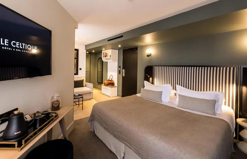 Une chambre d'hôtel moderne avec un grand lit et une télévision murale.