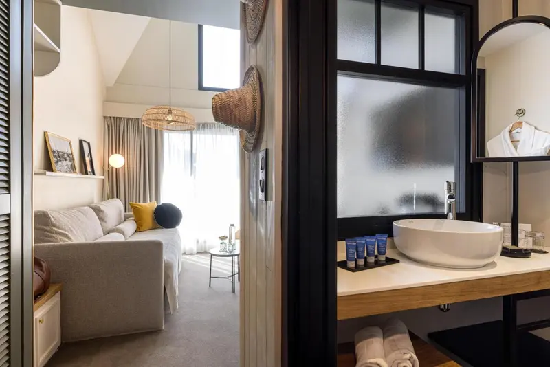 Une chambre lumineuse avec un canapé et une salle de bain attenante.