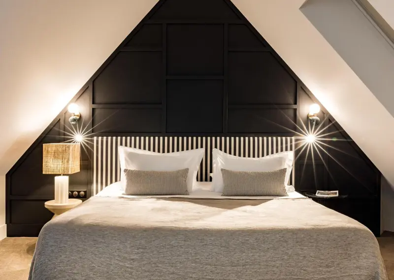 Un lit double est dispose dans une chambre mansardee au decor sobre.