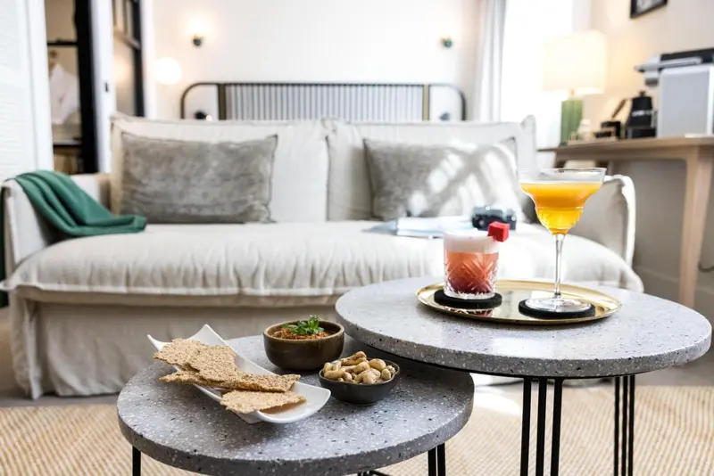 Une table basse avec des boissons et des amuse-gueules se trouve devant un canapé.