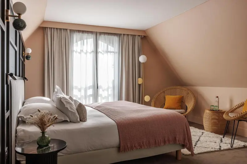 Une chambre à coucher lumineuse avec un lit fait et un fauteuil en rotin.