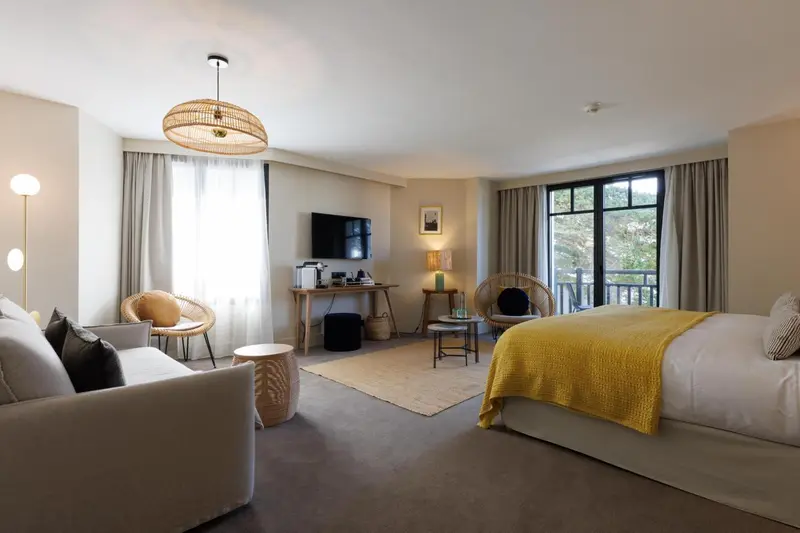 Une chambre lumineuse avec un canapé, un bureau et un grand lit recouvert d'une couverture jaune.