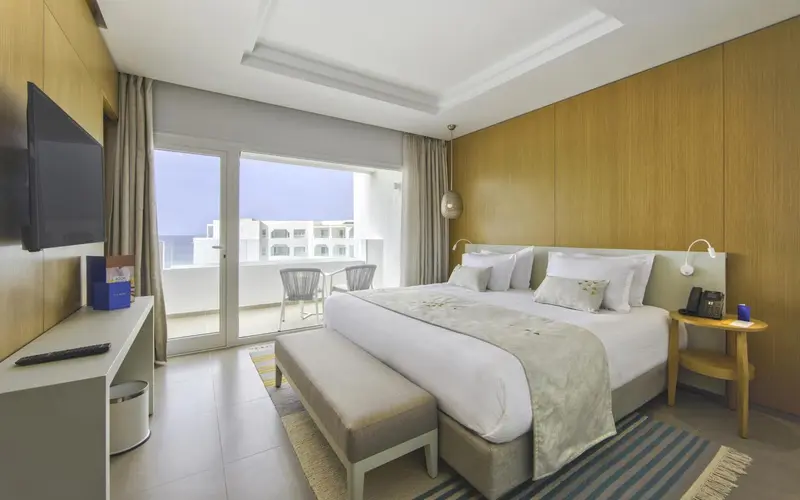 Une chambre lumineuse avec un grand lit et un accès à une terrasse.