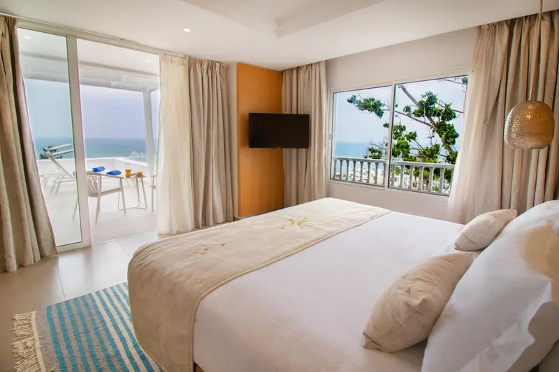 Chambre lumineuse avec un grand lit et une vue sur la mer.