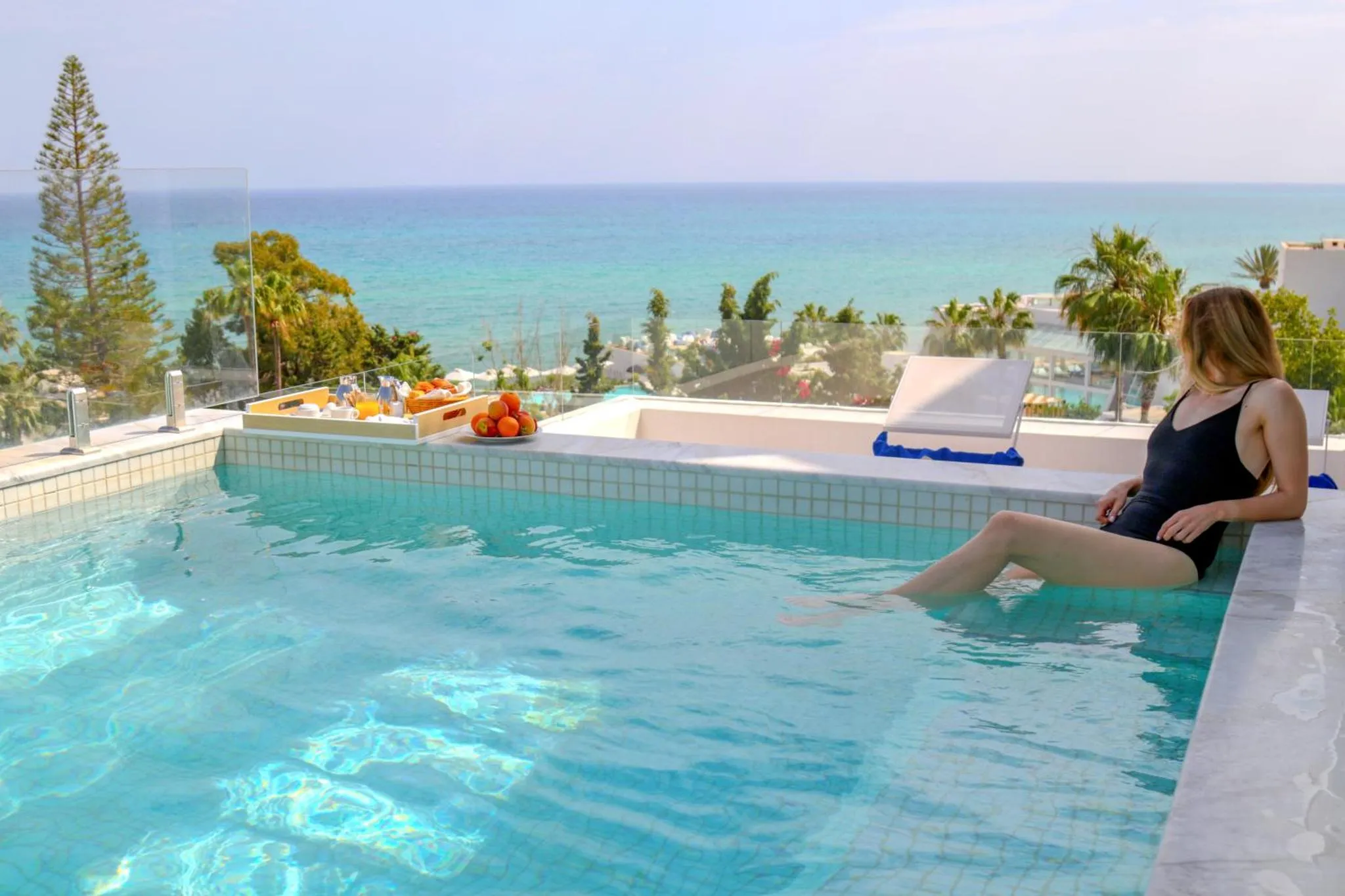 Une femme se détend au bord d'une piscine avec vue sur la mer.