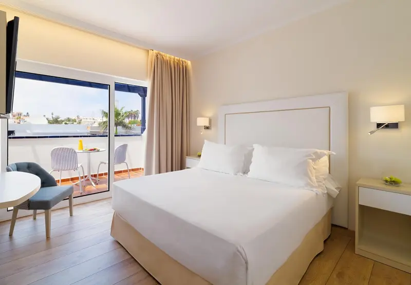 Une chambre lumineuse avec un grand lit et un balcon.