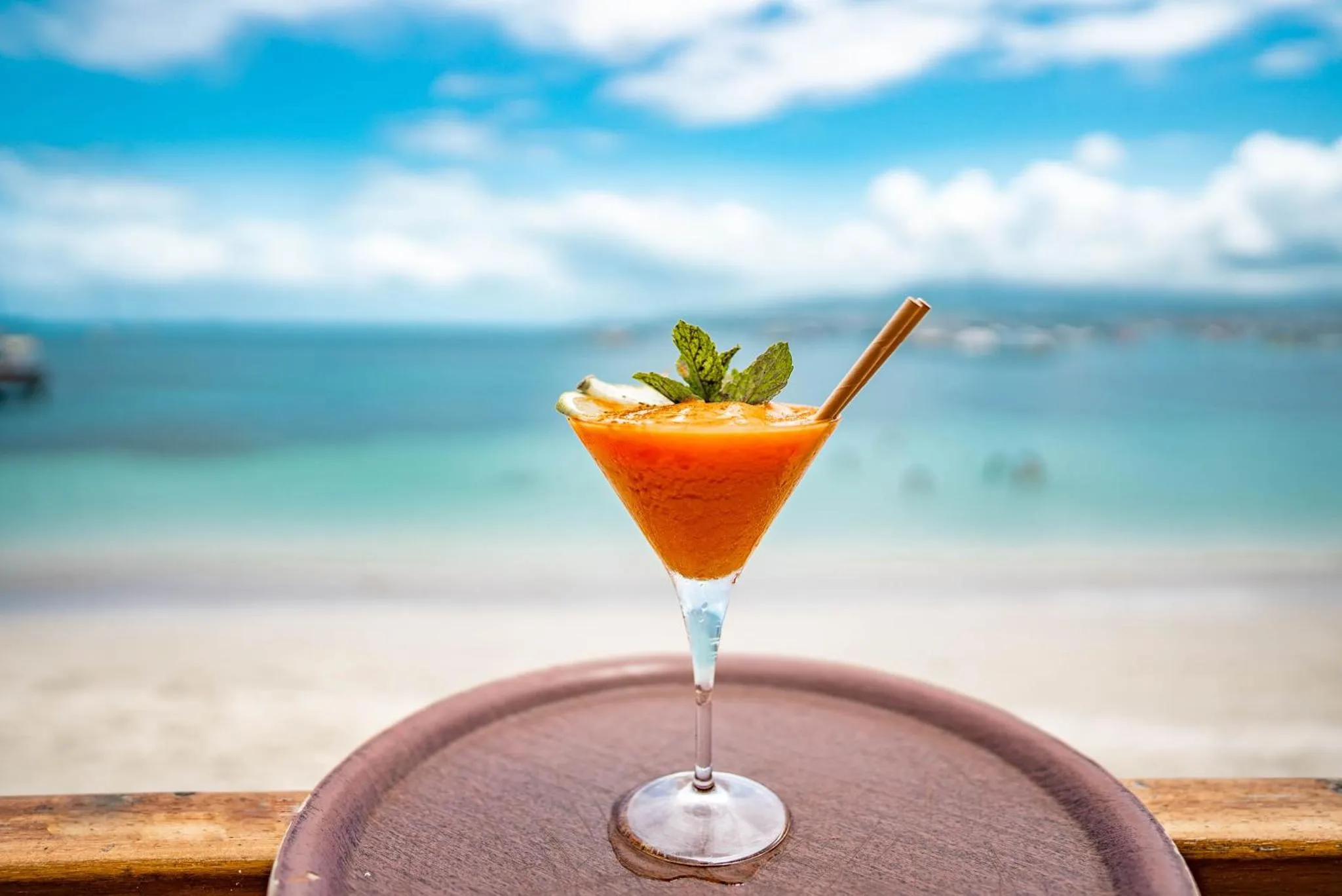 Un cocktail coloré est servi sur une terrasse avec vue sur la mer.