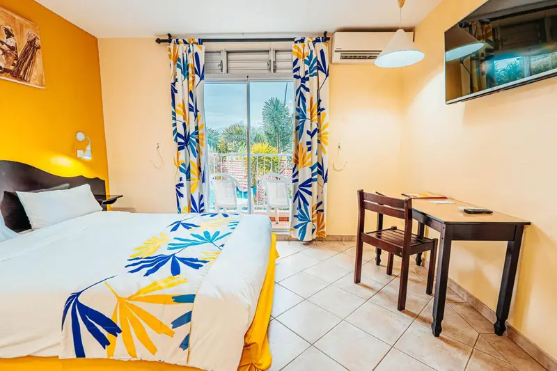 Chambre lumineuse avec un lit double et un coin repas.
