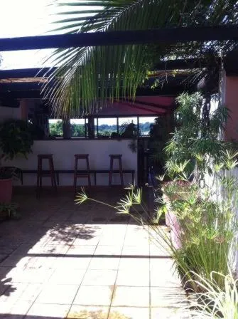 Terrasse ombragée avec des tabourets de bar et une végétation luxuriante.