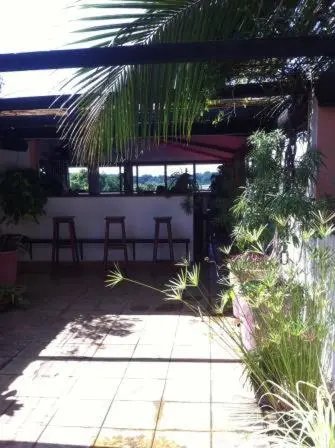 Terrasse ombragée avec des tabourets de bar et une végétation luxuriante.
